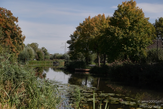 A serene landscape in the Netherlands featuring a winding river with trees and a small bridge in - image from year 2025 #003