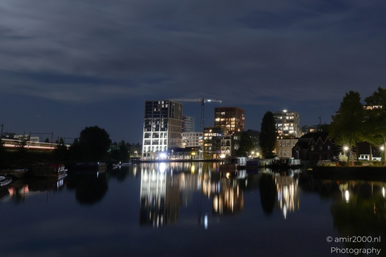 Nighttime view across water in Amsterdam, Netherlands, showing illuminated buildings and - image from year 2025 #002