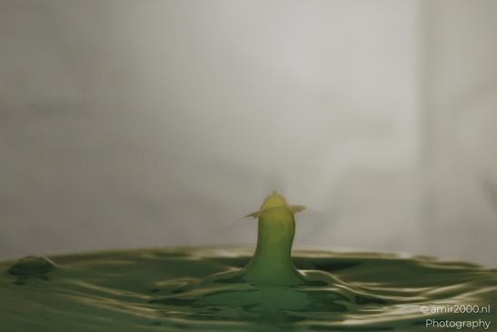 Water drops creative series: dancing yellow droplet amidst greenish-blue ripples. . - image from year 2025 #007
