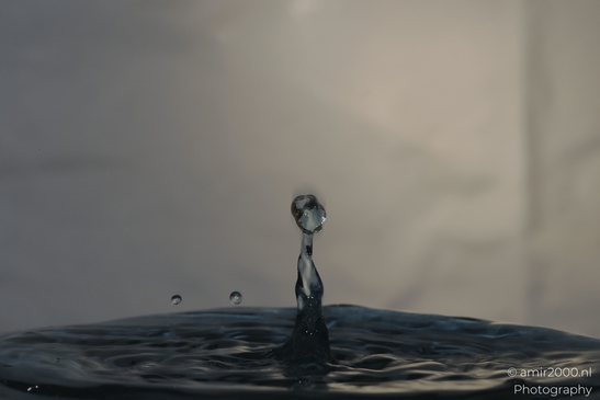 A single water droplet splashes against a backdrop of other droplets, creating an artistic image - image from year 2025 #033