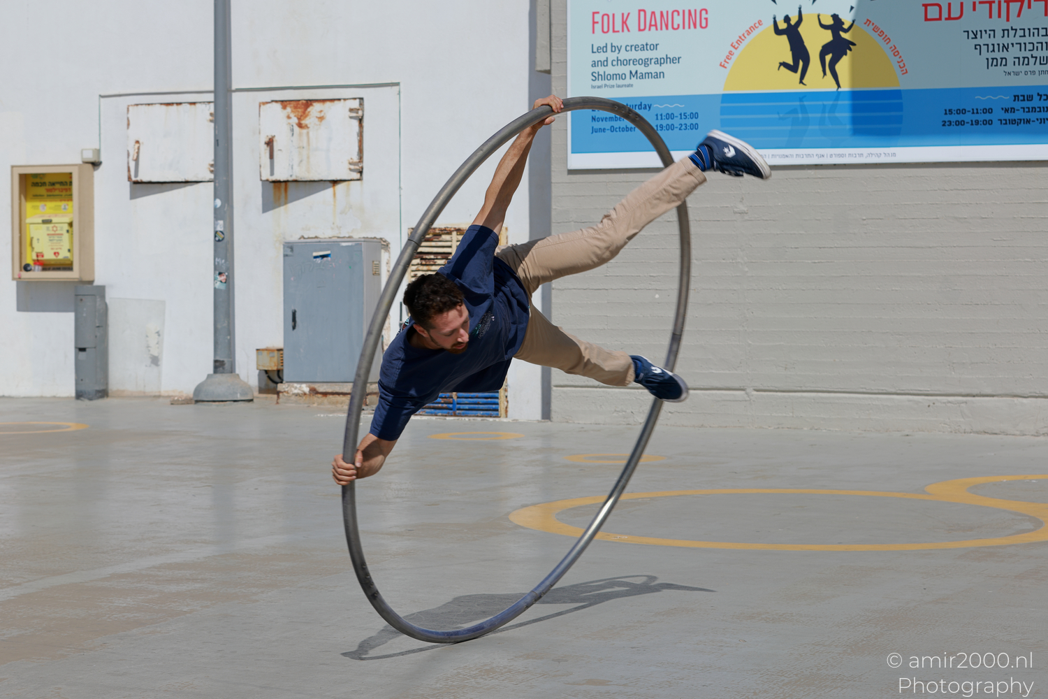 Male Cyr wheel acrobat leaning sideways inside a rolling hoop in Tel Aviv-Jaffa