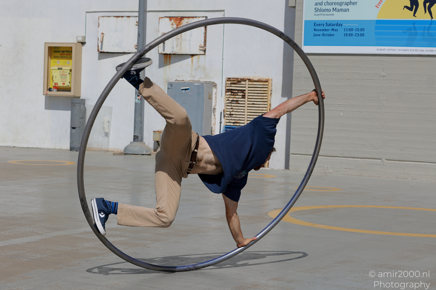 Male Cyr wheel acrobat extending one leg above the hoop in Tel Aviv-Jaffa
