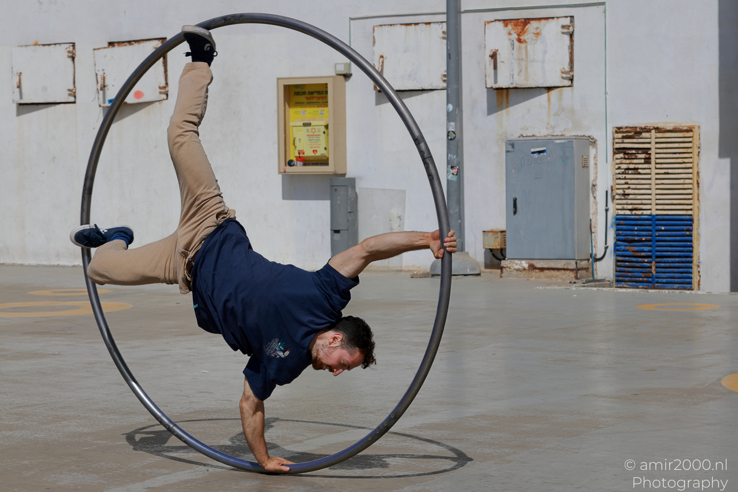 Male Cyr wheel acrobat balancing on one hand inside the hoop in Tel Aviv-Jaffa