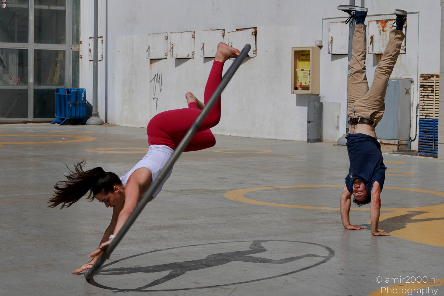 Two acrobats performing simultaneous handstands beside a Cyr wheel in Tel Aviv-Jaffa