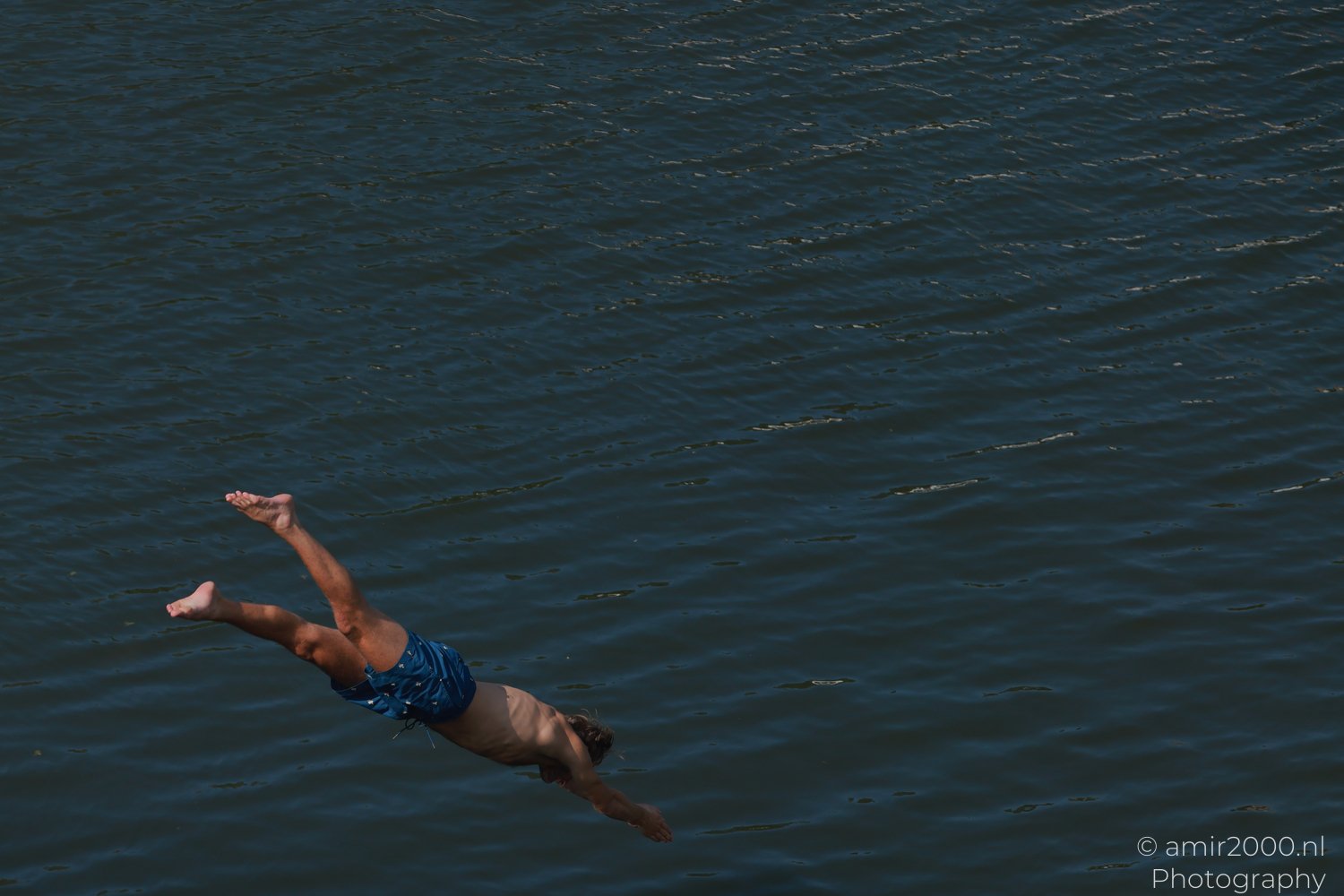 Man jumping head first into an Amsterdam canal from a dock
