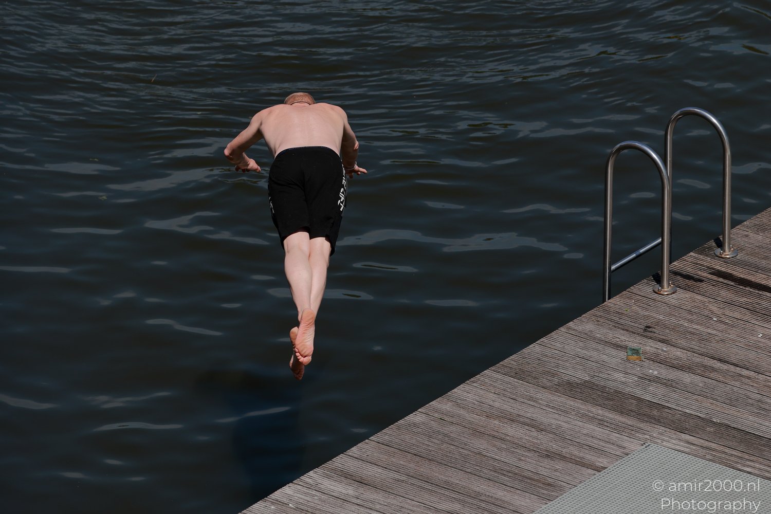Man diving into an Amsterdam canal during a hot summer day