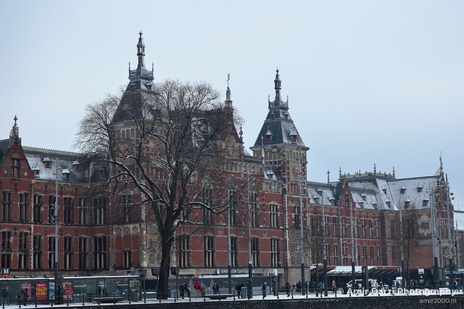 An old red brick building featuring pointed towers and ornate detailing serves as a transportation hub.