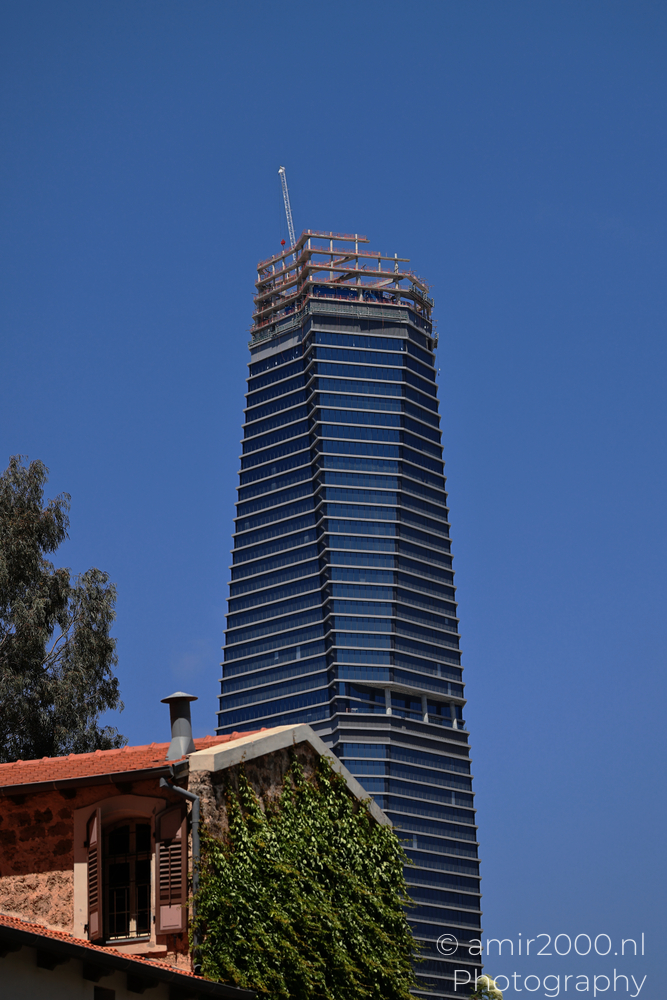 ToHa 2 tower rising behind old stone house and ivy in Tel Aviv-Jaffa