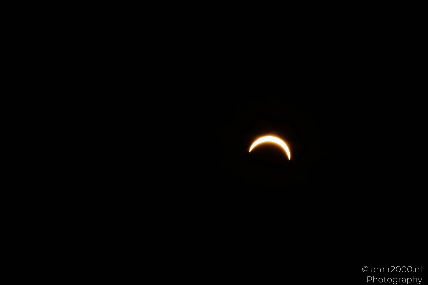 Fine crescent of the Sun isolated in the dark sky as the Moon crosses its face.