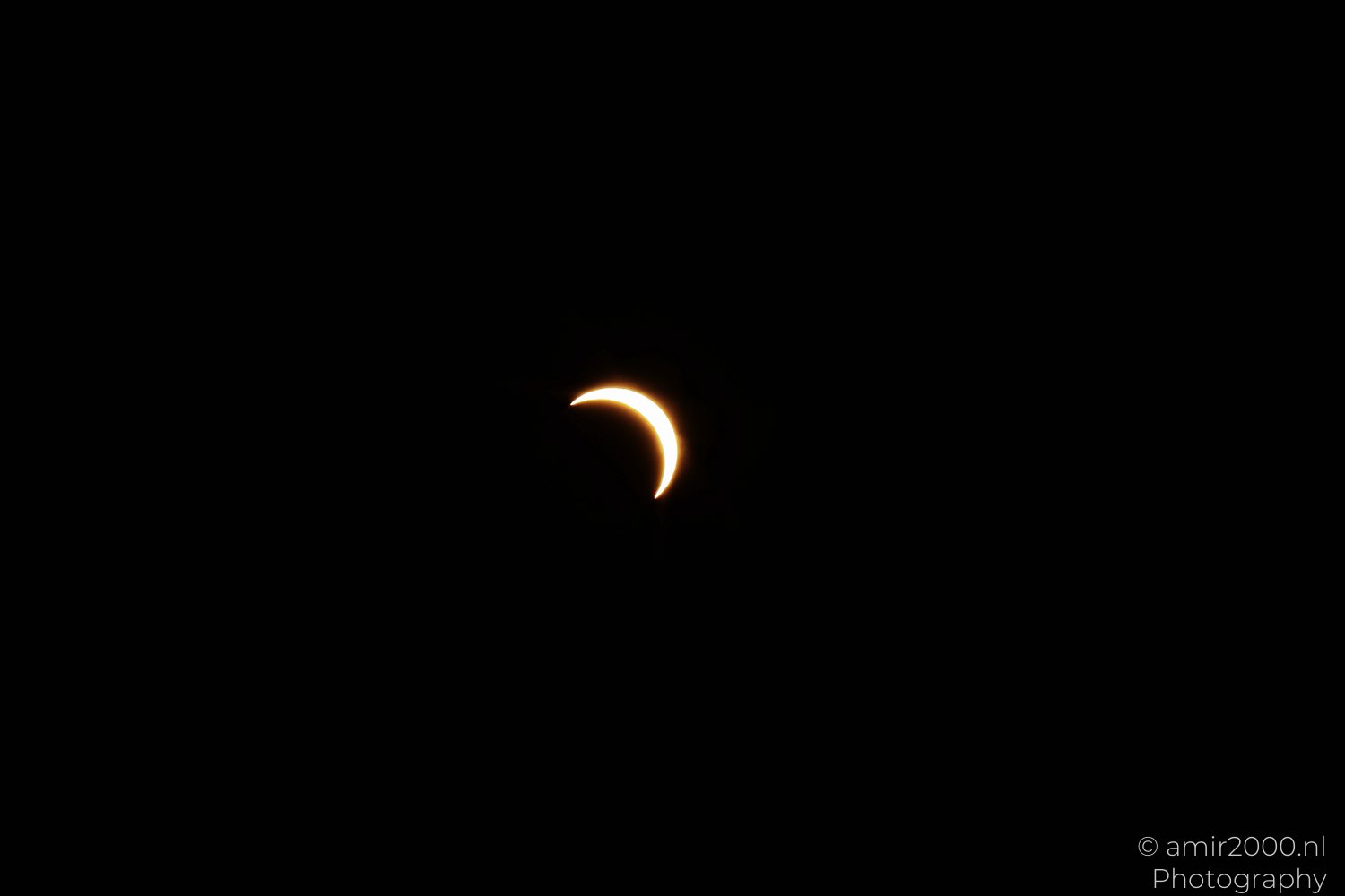 Small bright solar crescent against black, created by the Moon's silhouette.