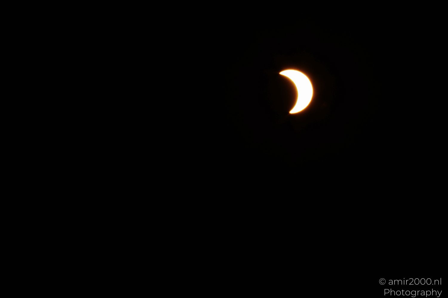 Bright C-shaped solar crescent with the Moon covering most of the Sun.