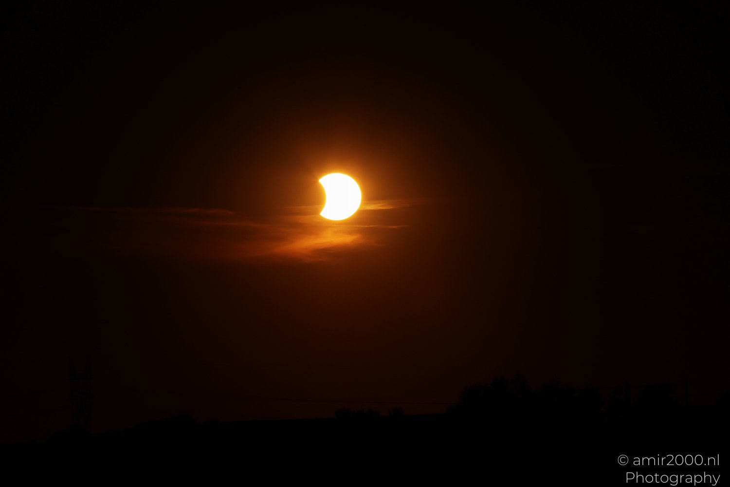 Partially eclipsed Sun glowing above Amsterdam at orange twilight