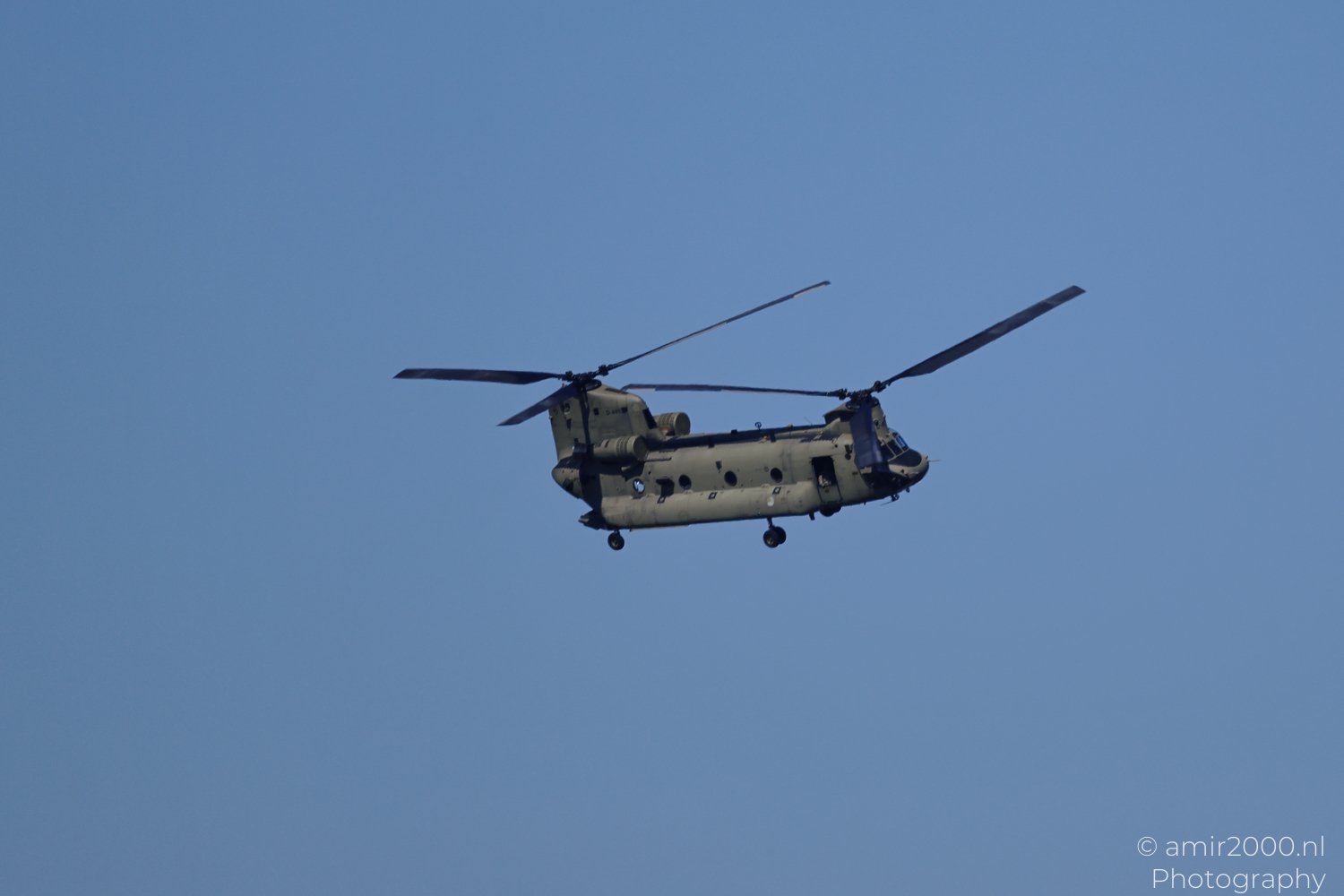 Royal Netherlands Air Force Boeing CH-47 Chinook helicopter in flight during a low pass over the urban area from a wide composition.