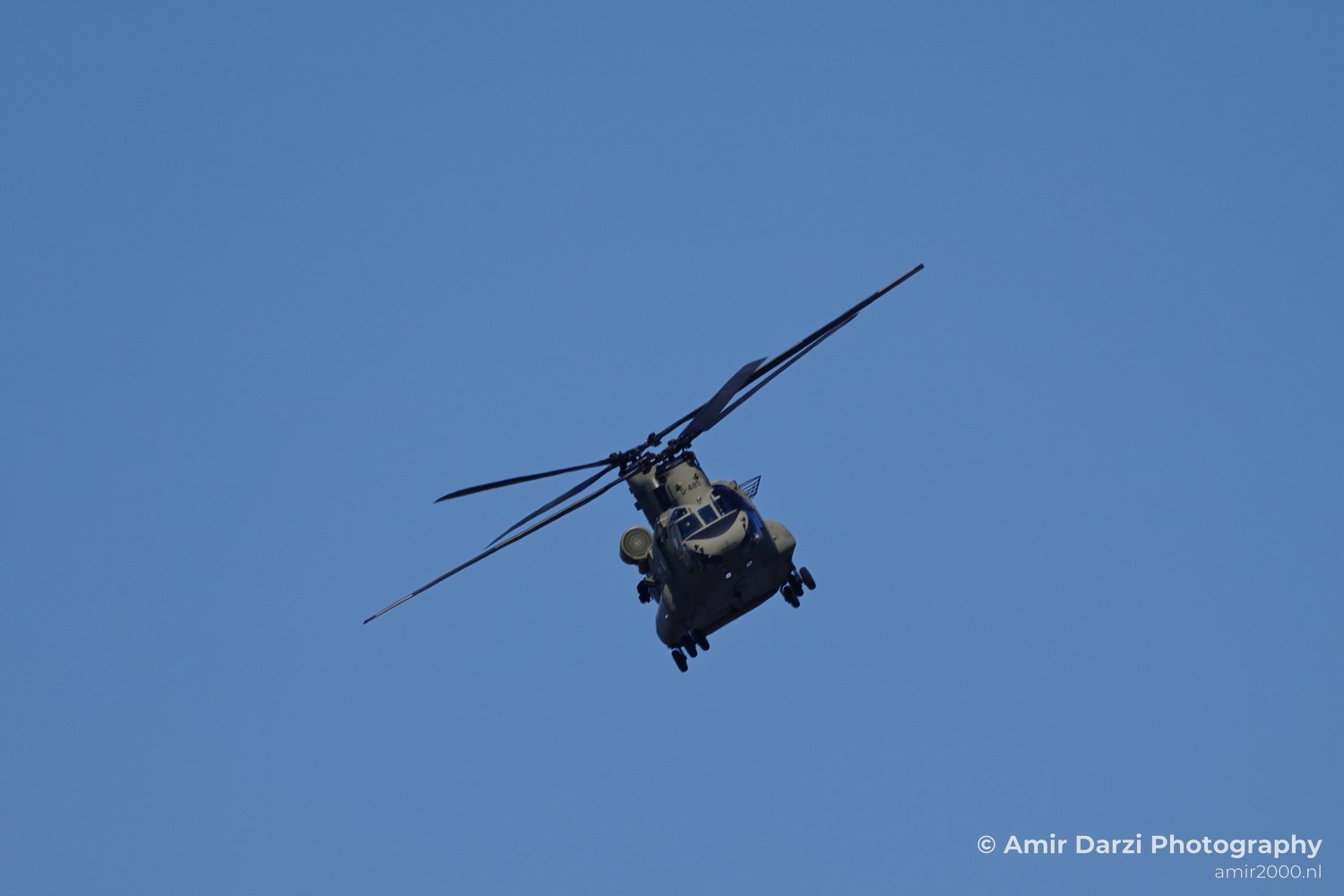 Royal Netherlands Air Force Boeing CH-47 Chinook helicopter banking across the sky with air force markings visible from a wide composition.