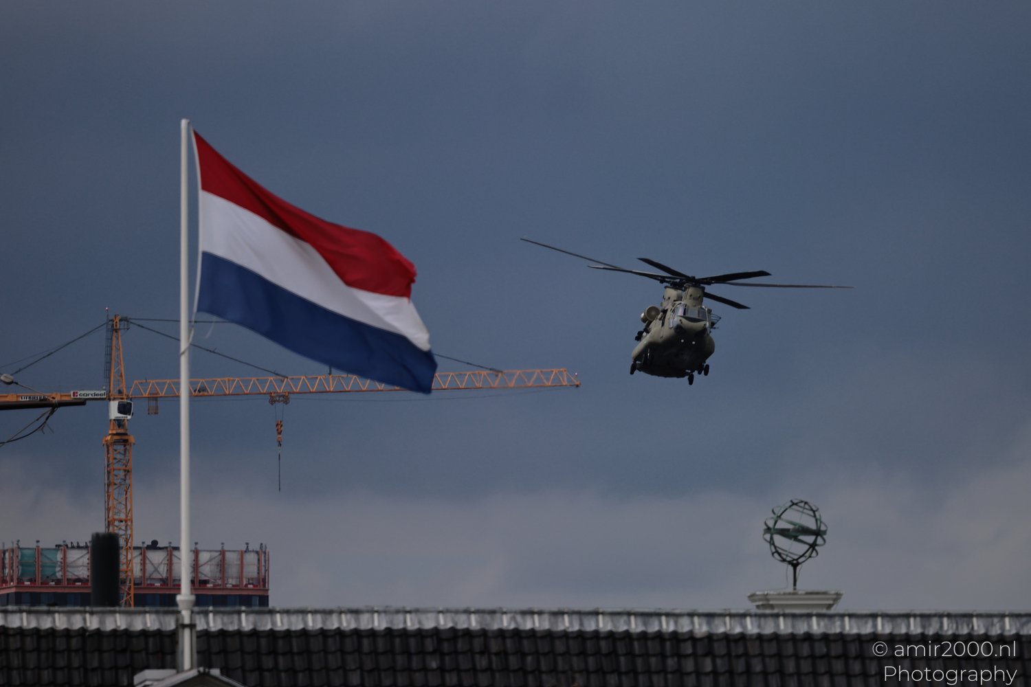Royal Netherlands Air Force CH-47F Chinook flying near a Dutch flag in Amsterdam