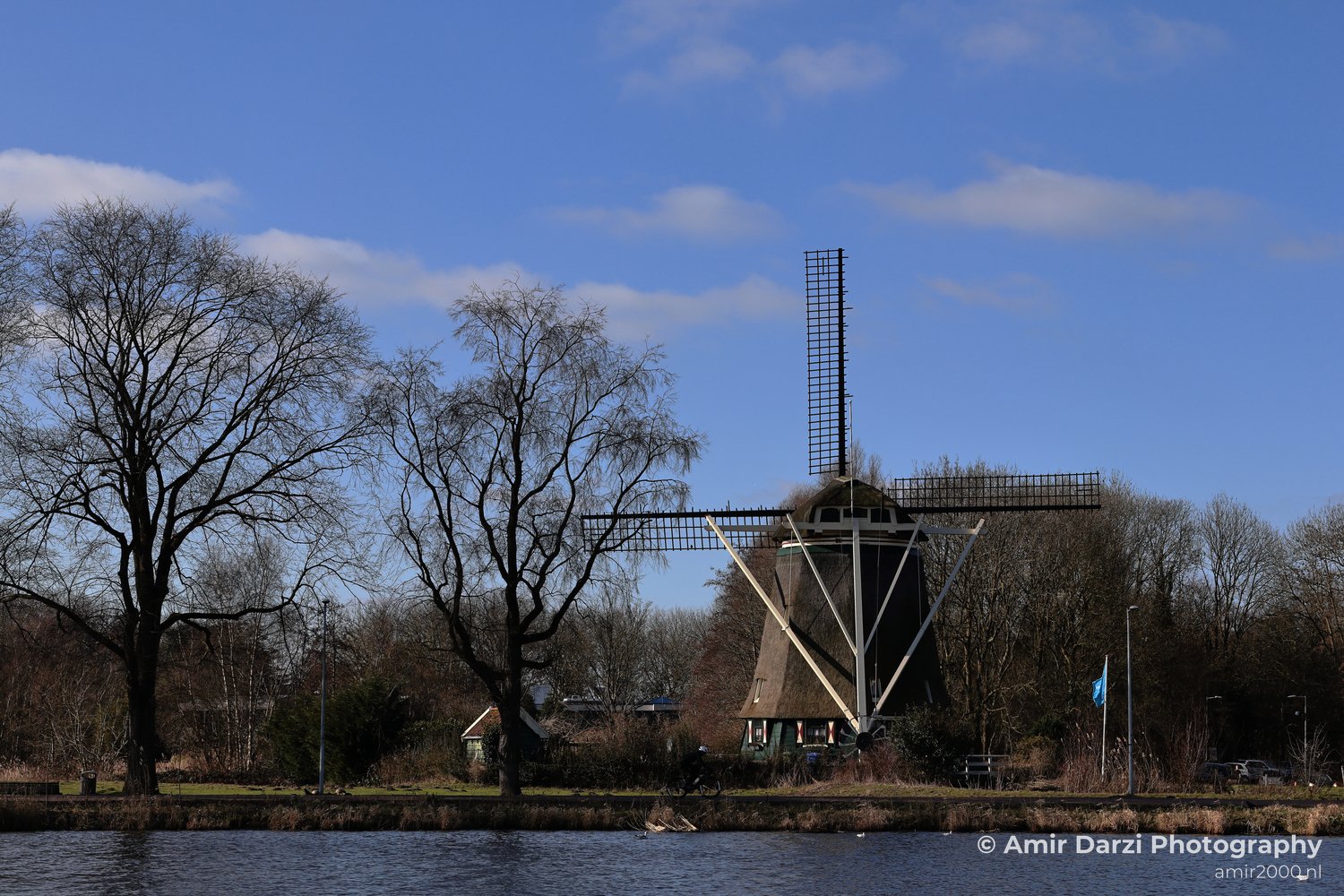 De Riekermolen 1636 windmill with a large lattice structure stands on the Amstel river.