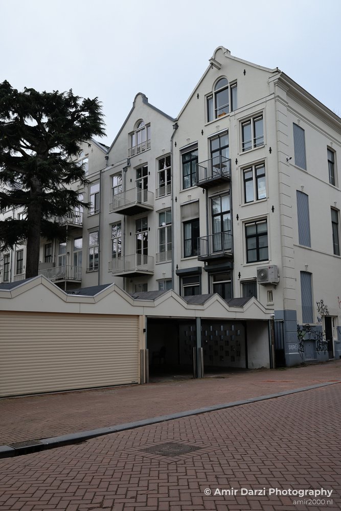 Residential building facade with multiple windows, balconies, and a garage entrance on a city in Amsterdam.