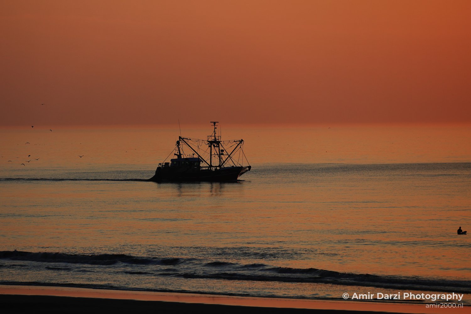 Orange sky with fishing boat, calm waters, and north sea.
