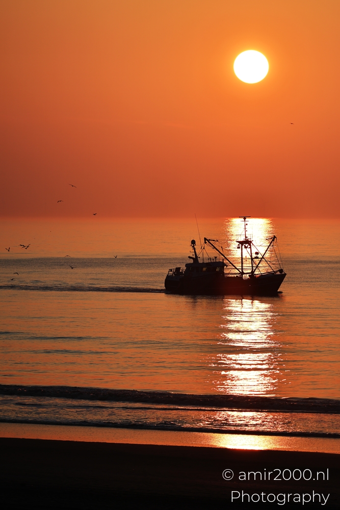 Fishing boat crossing sunset reflection near the Zandvoort shoreline