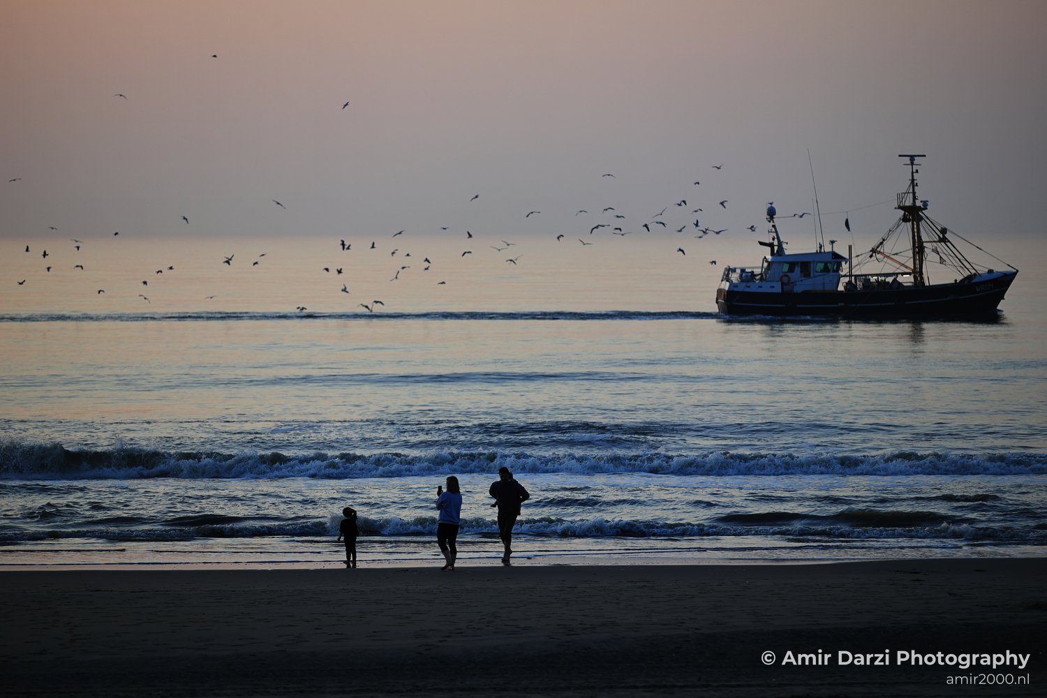 A scene featuring sunset alongside people, water, sky, beach and boat.