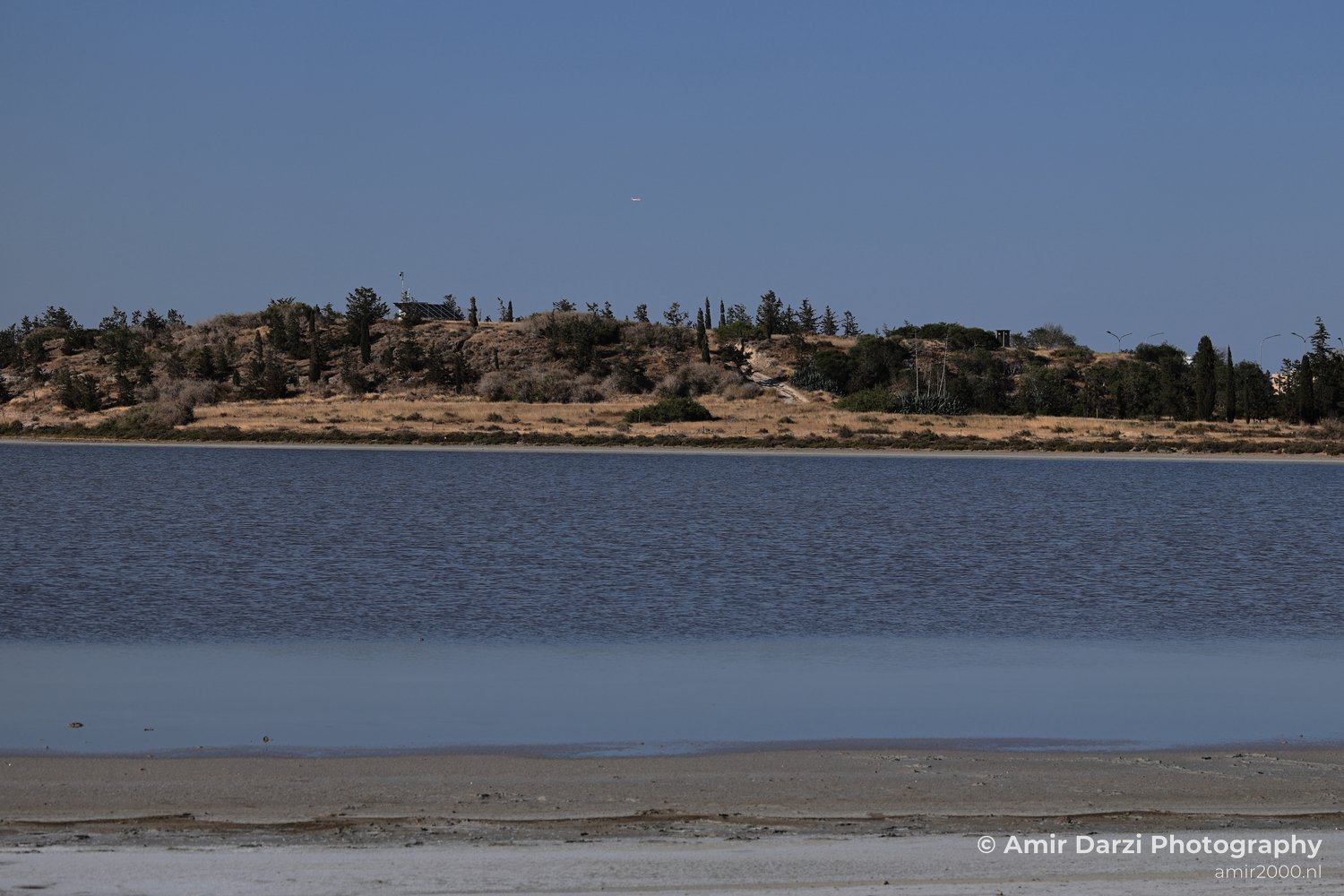 A saltwater body with an island in the distance under a bright sky.