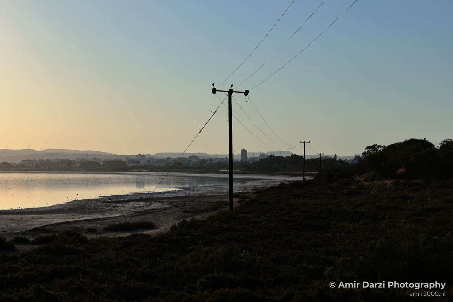 Power lines stretch across a salt lake at dusk.