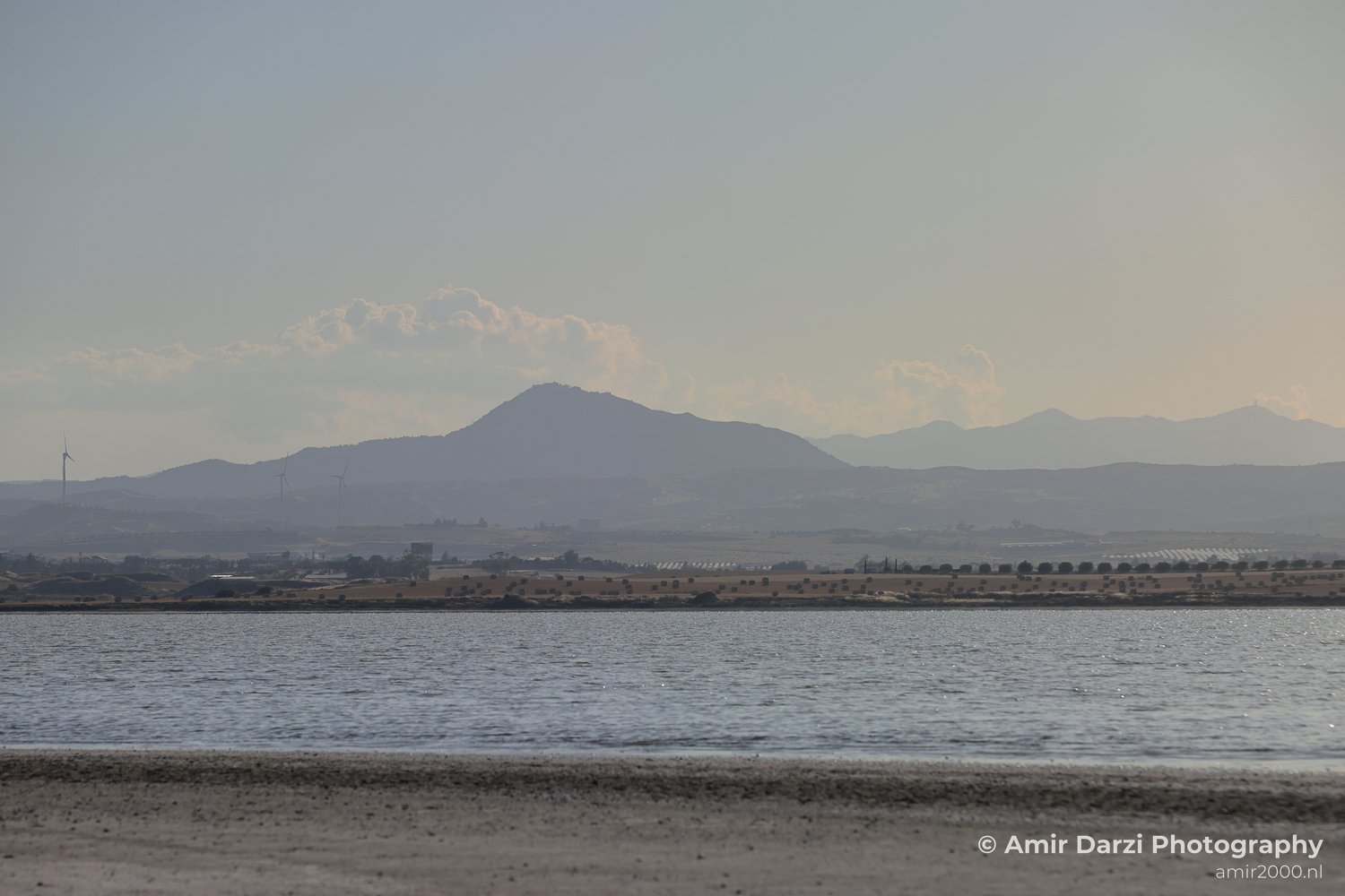 A seascape featuring a mountainous backdrop and a sandy beach.