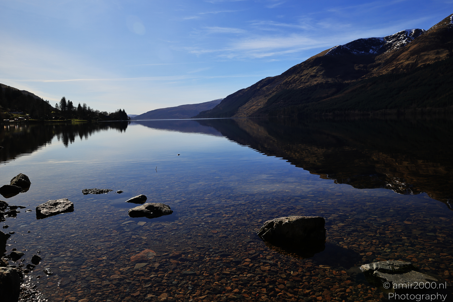 Shallow Loch Lochy water with stones and reflected Highland ridges