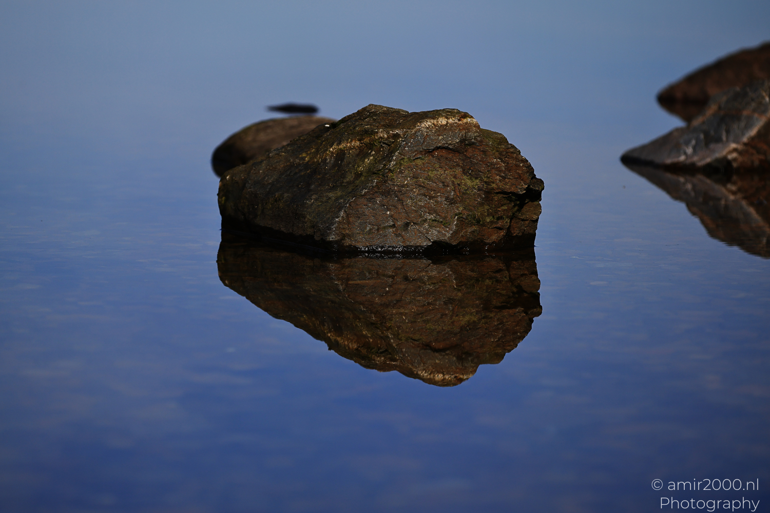 Partly submerged rock reflected in calm Loch Lochy water