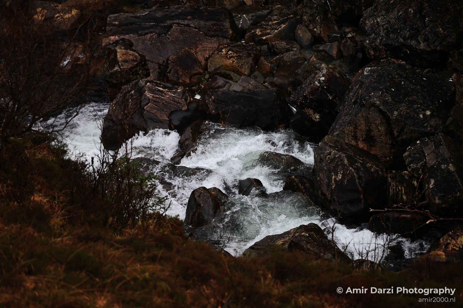 Some vegetation on either side of the stream appear with the river flowing through rocky terrain in Scotland United Kingdom.