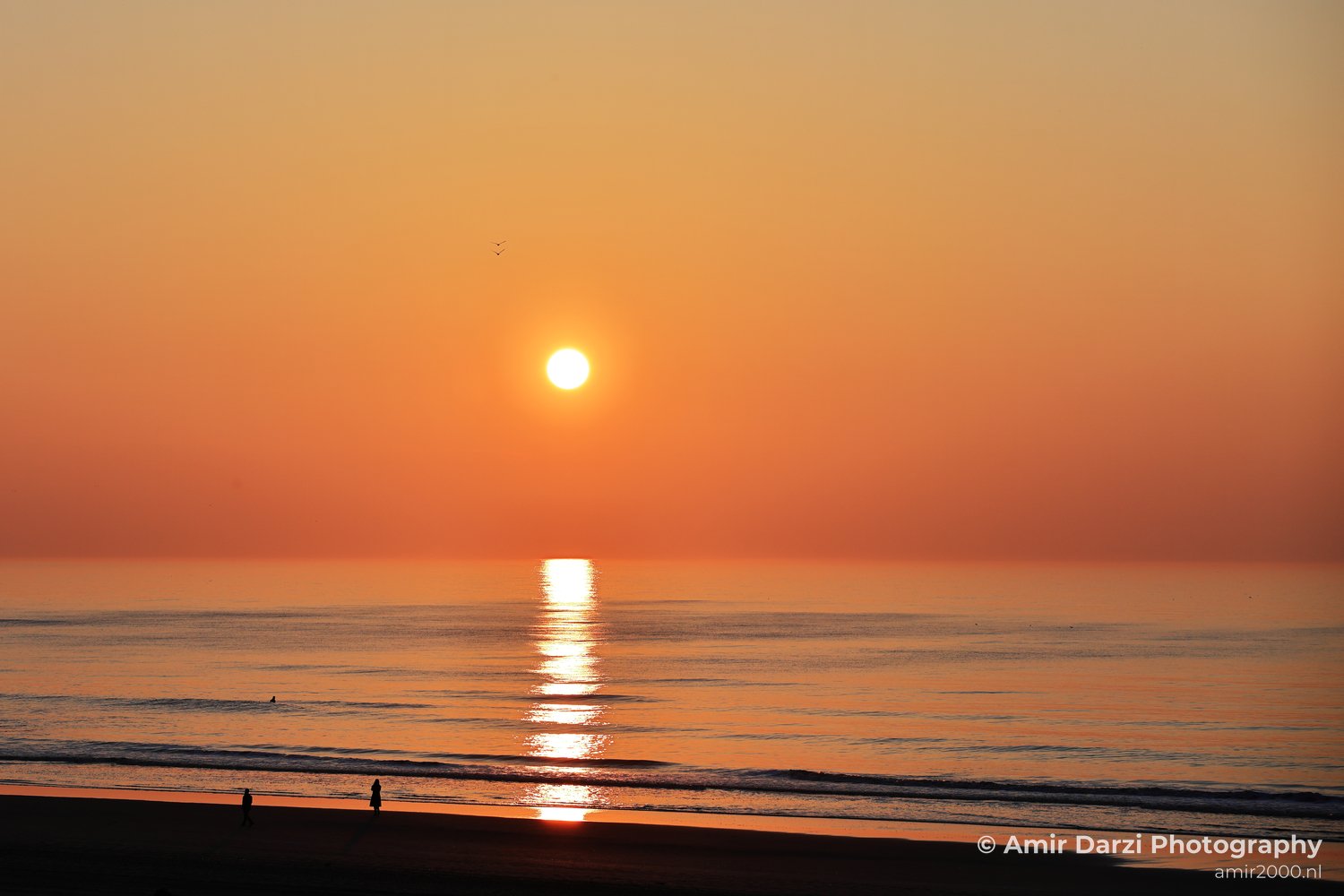 A sunset over the North Sea, with the sun setting low and the water reflecting the warm hues of the sky.