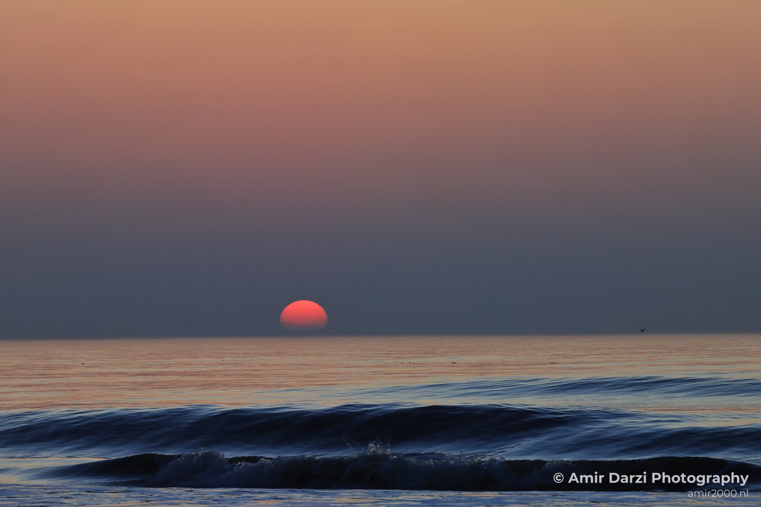 Orange glow with calm waters, north sea, and horizon.