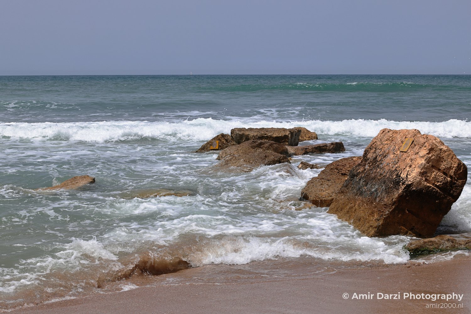 A coastal view featuring rocky formations and gentle ocean waves.