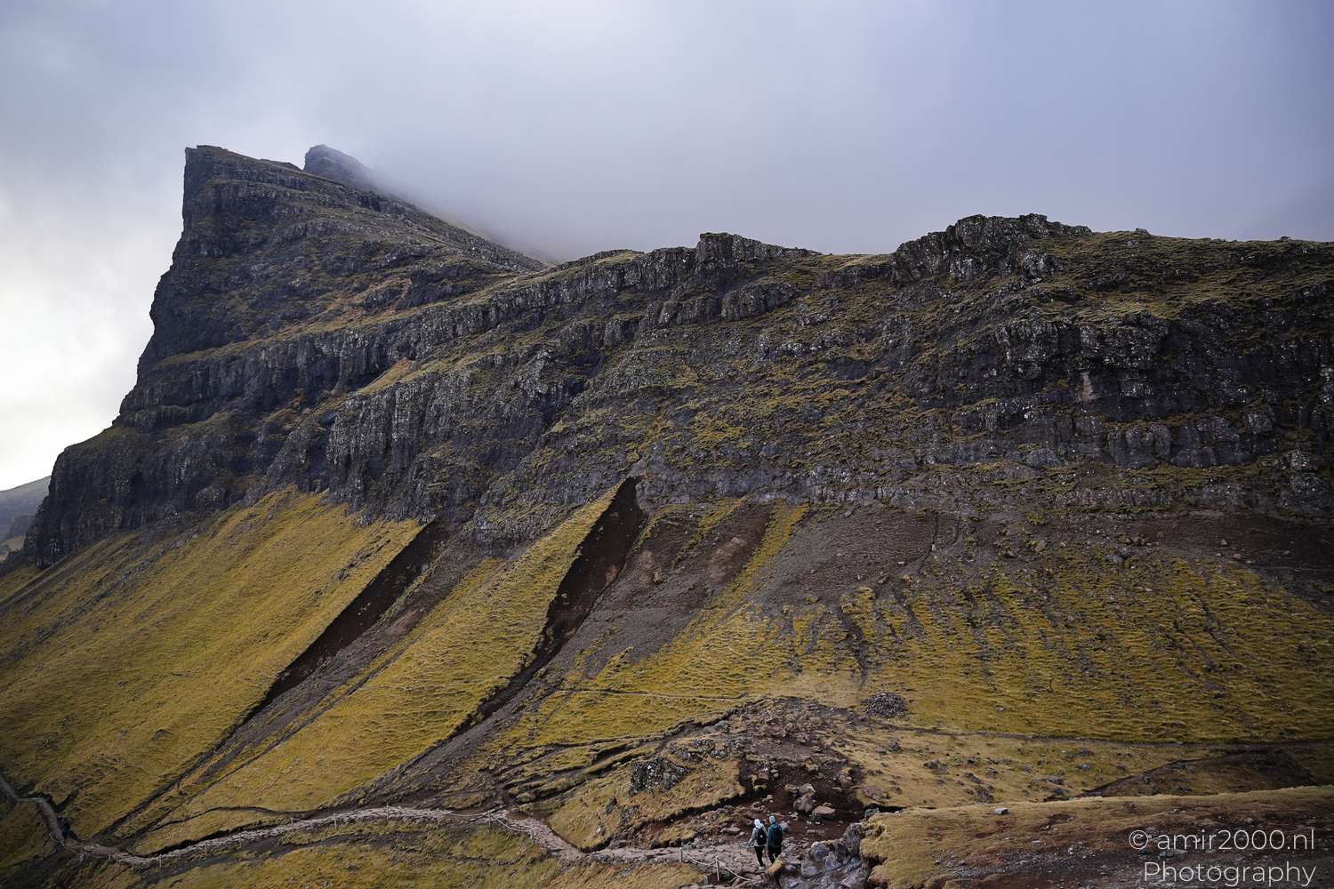 Hikers walking below cliffs near Old Man of Storr on Isle of Skye