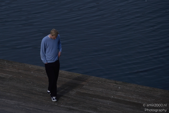 A young man in casual attire on a dock, gazing at the water. image from year 2026 #1