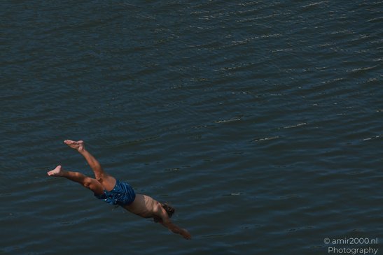 A person in blue swim trunks is diving into a body of water in Amsterdam, Netherlands. - image from year 2026 #002