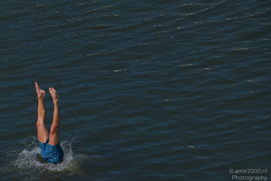 A person wearing blue swim trunks is diving into a body of water, with their legs extended - image from year 2026 #003