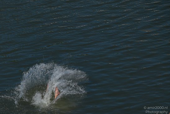 A person is partially submerged in water, creating a splash as they move in Amsterdam, - image from year 2026 #004