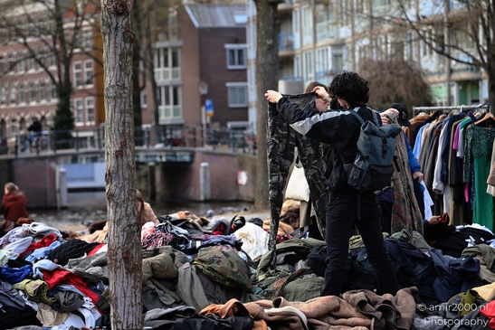 People standing over a pile of clothes in an outdoor setting, likely a clothing sale in - image from year 2026 #001