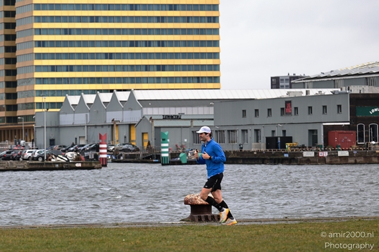 Jogging man on riverside path with urban buildings in background. image from year 2026 #1