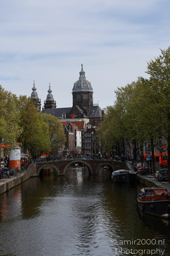 A canal with boats and a bridge, reflecting the surrounding buildings in Amsterdam, Netherlands. - image from year 2026 #006