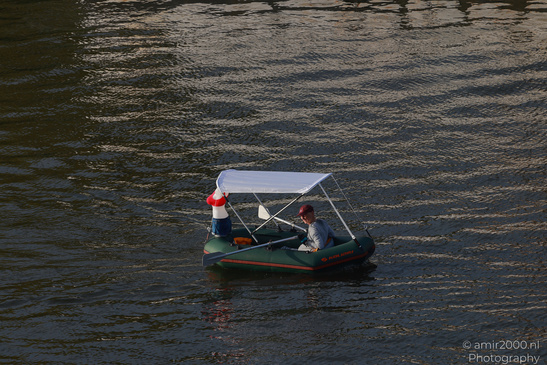 A small inflatable boat with a canopy is floating on the water in Amsterdam, Netherlands. - image from year 2026 #027