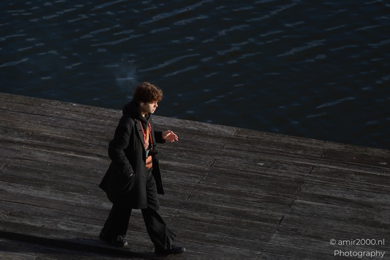 A solitary figure walks along a wooden dock by the water at dusk. - image from year 2026 #002