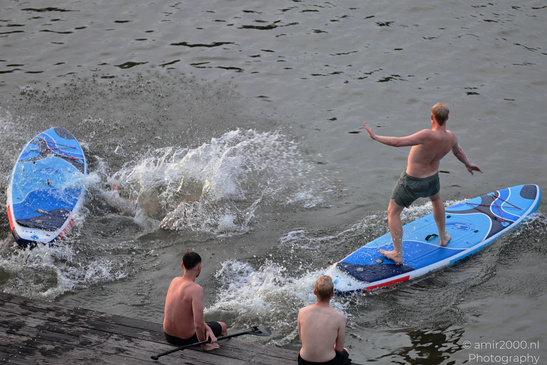 A paddleboard while another individual falls into the water nearby includes the person standing in image from year 2026 #12