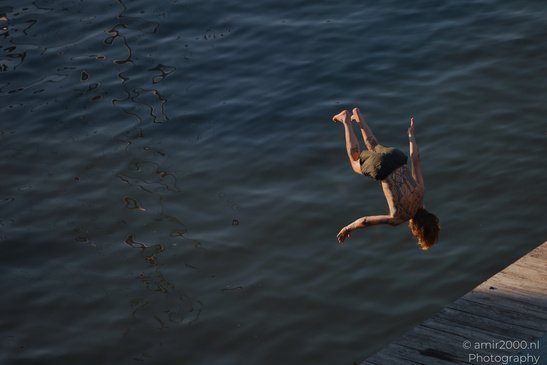 A person with tattoos is diving into a water from a dock in Amsterdam, Netherlands. - image from year 2026 #002