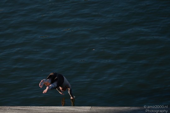 A person is diving into a body of water from a dock in Amsterdam, Netherlands. - image from year 2026 #002