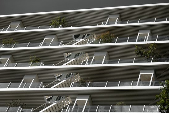 A modern building with horizontal slats and greenery on the balconies in Amsterdam, Netherlands. - image from year 2026 #001