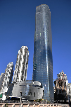 A modern glass skyscraper standing prominently against a clear blue sky, surrounded by other - image from year 2026 #002