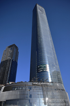 A tall glass skyscraper with a sign that reads "BEYOND TOWER COMING SOON" and another building - image from year 2026 #005