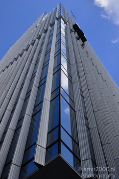 A towering skyscraper with reflective glass windows and blue sky backdrop. - image from year 2026 #002